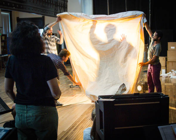 Director and ensemble member Tina Landau watches the cast play with shadows